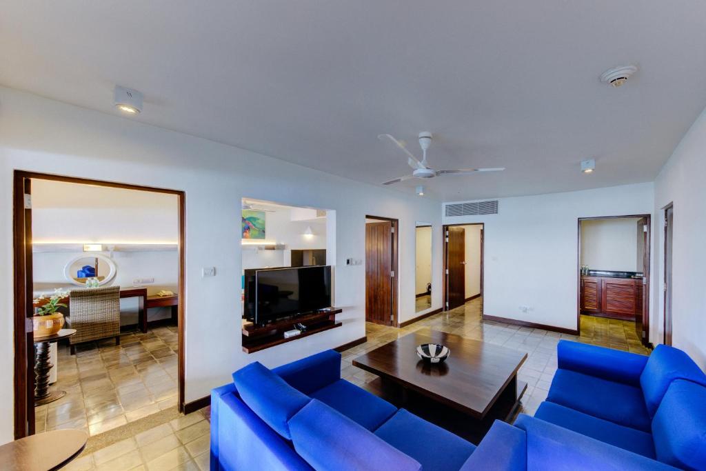 a living room with a blue couch and a table at Hikka Tranz by Cinnamon in Hikkaduwa