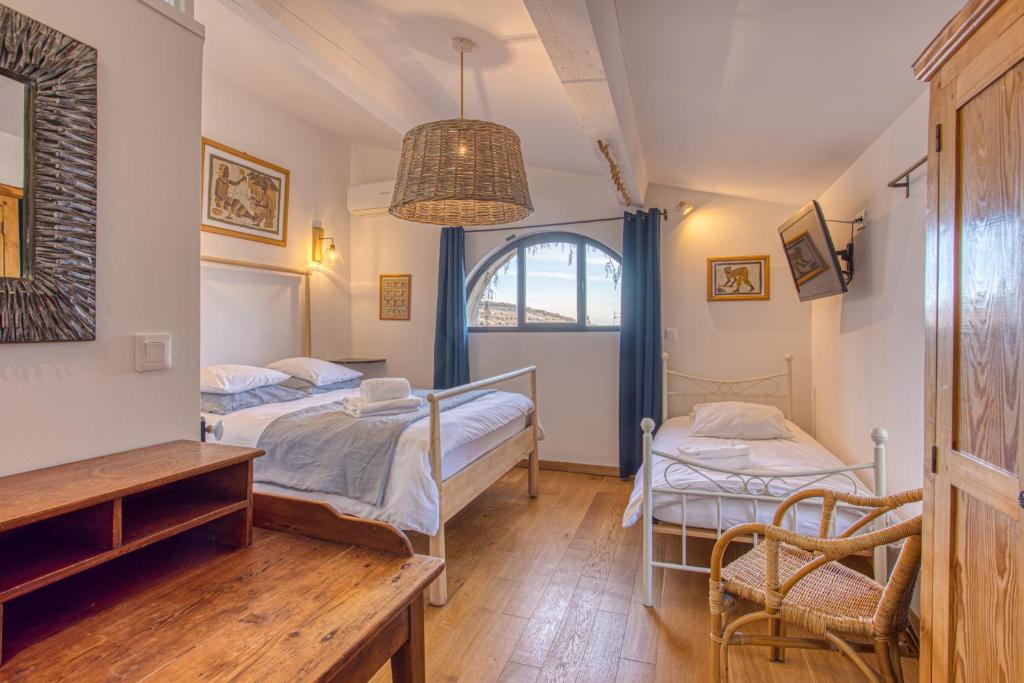 sypialnia z 2 łóżkami, stołem i krzesłami w obiekcie Hôtel Restaurant Les Remparts w mieście Venasque