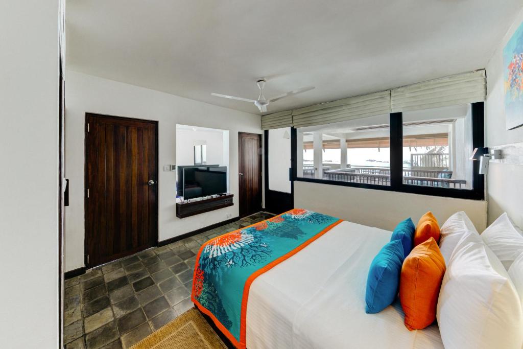 a bedroom with a large bed with orange and blue pillows at Hikka Tranz by Cinnamon in Hikkaduwa