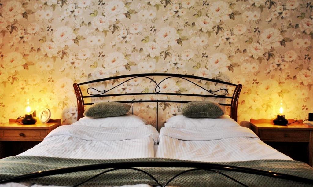 a bed in a bedroom with flowers on a wall at Pokrzepka in Spychowo