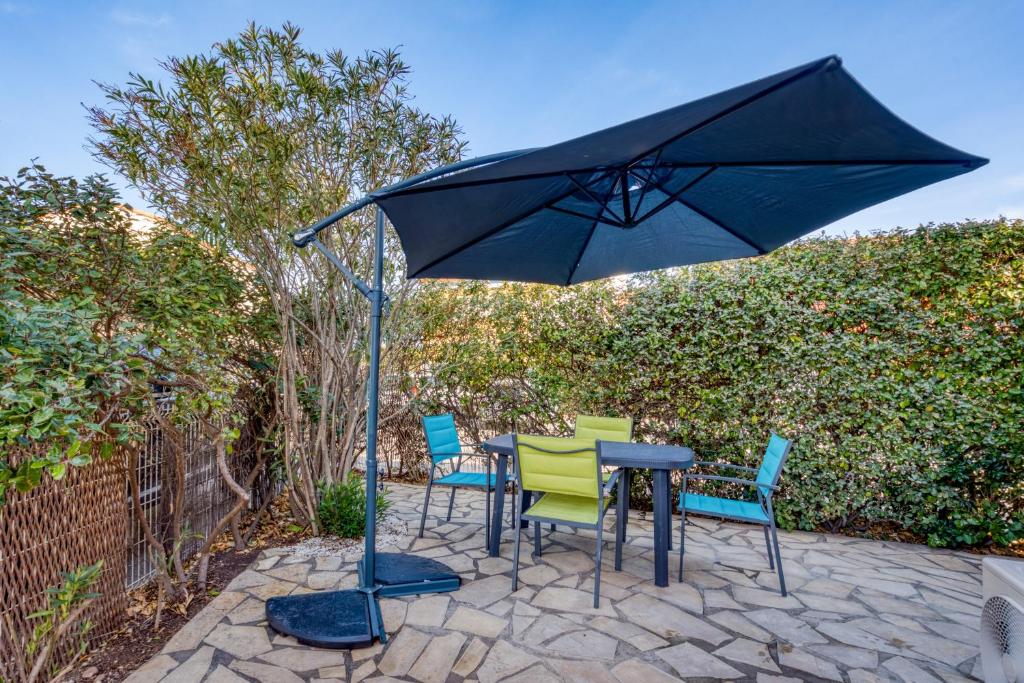- une table et des chaises sous un parasol sur la terrasse dans l'établissement Le Mas de la Mer, à Frontignan