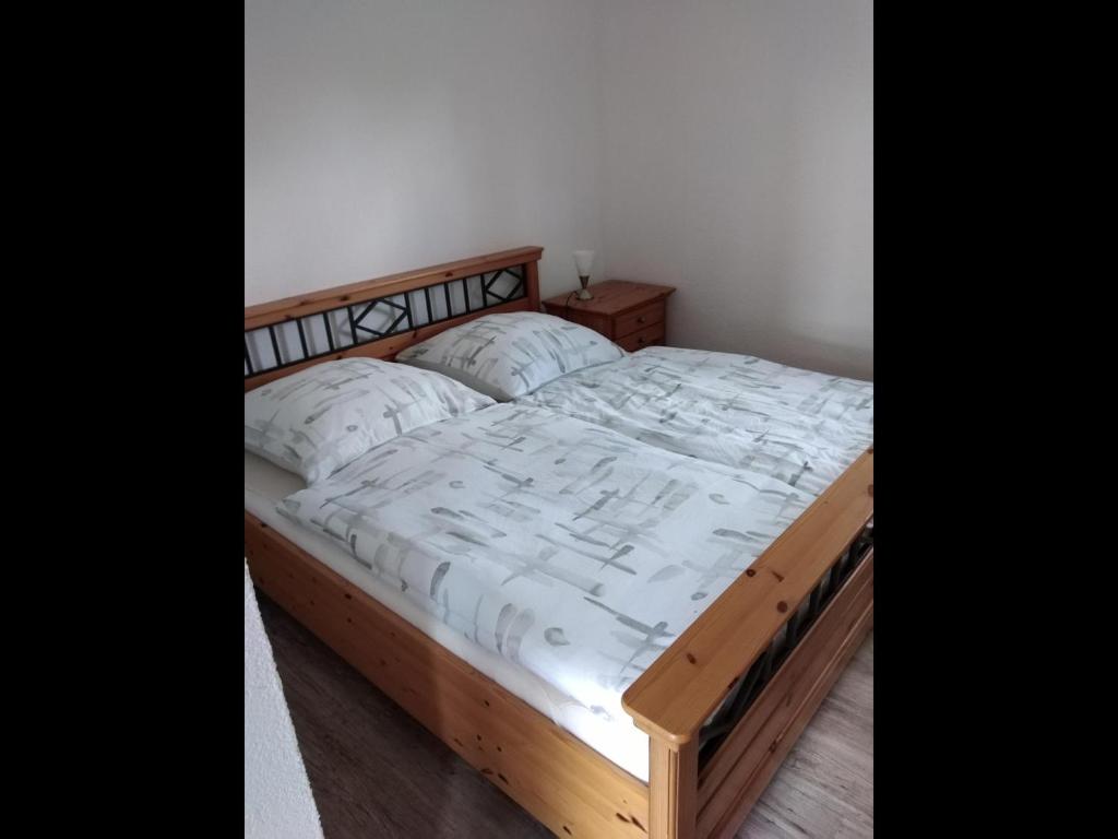 a bed with a wooden frame and white sheets and pillows at NEU! See-Ferienwohnung 1 in Großmöhlau