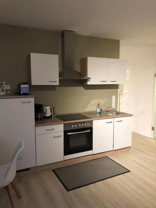 a kitchen with white cabinets and a stove top oven at Ferienwohnung mit Blick auf den Feldberg in Weilmünster