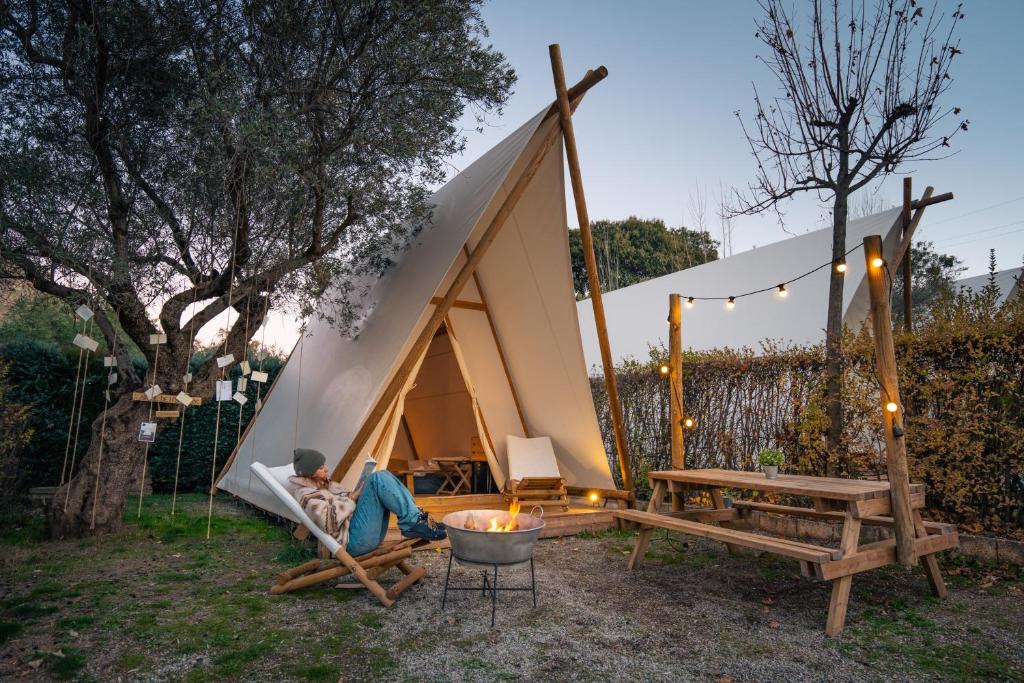 a man sitting in a hammock in front of a tent at Kampaoh Sierra Nevada in Güéjar-Sierra