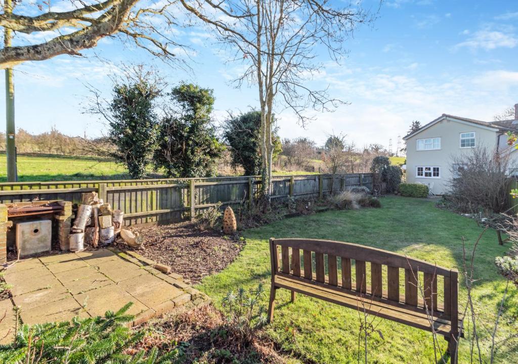 a park bench in a yard with a fence at Valentine Cottage in Snape