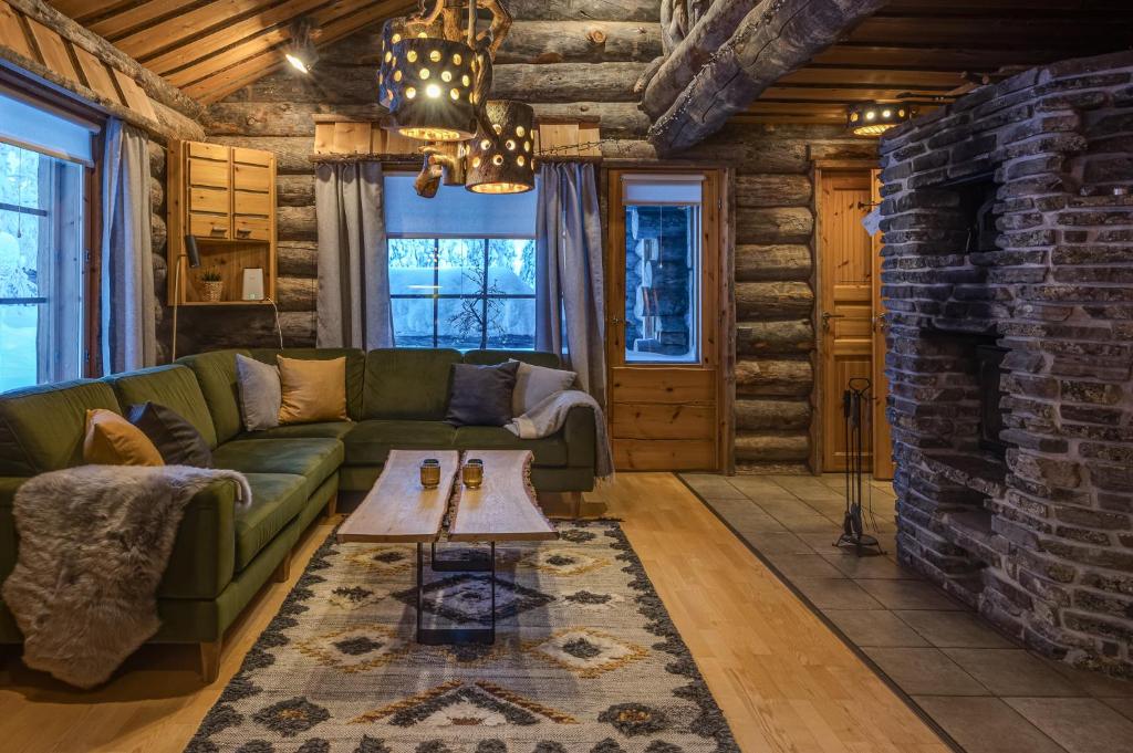 a living room with a green couch and a brick fireplace at Kuusirinne 2A - a log cabin near the slopes of Ruka in Ruka