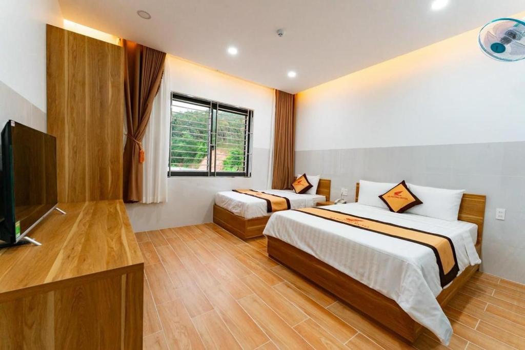 KHÁCH SẠN HÀ PHƯƠNG في Tánh Linh: غرفة نوم بسريرين وتلفزيون بشاشة مسطحة