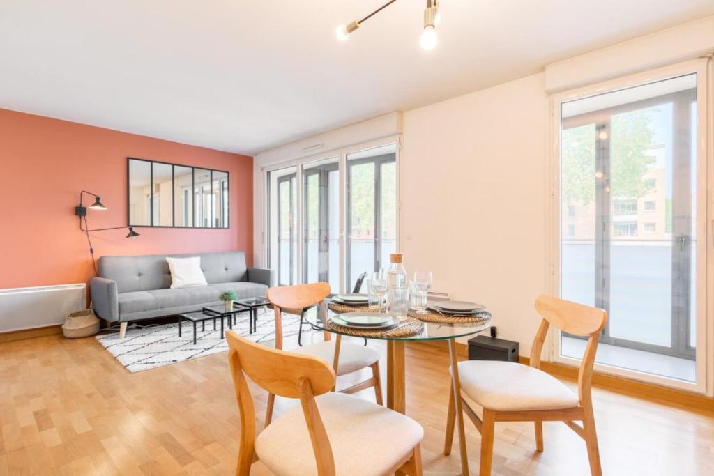 ein Wohnzimmer mit einem Tisch, Stühlen und einem Sofa in der Unterkunft Euratechnologies - Bright apartment with parking in Lille
