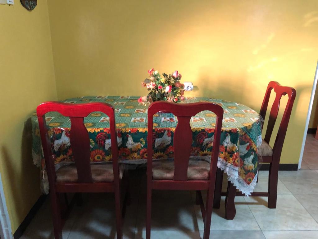a dining room table with two chairs and a table with a flower arrangement at Logerthine Studio Suriname in Paramaribo