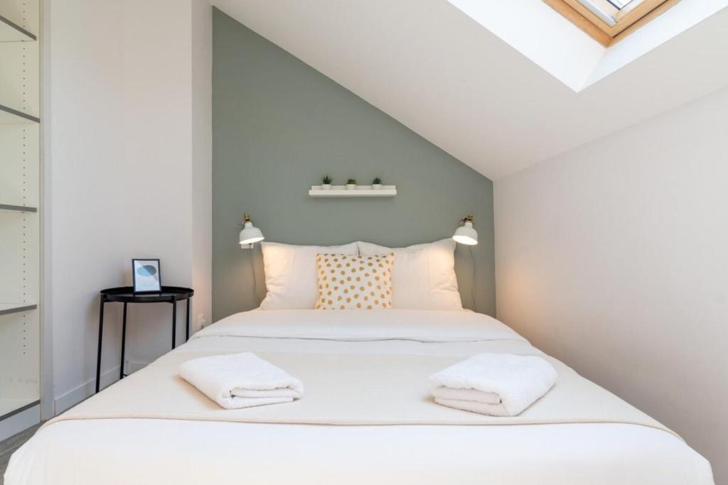une chambre avec un lit avec des draps blancs et des oreillers dans l'établissement Lille Hypercentre / Gares - Beautiful duplex!, à Lille