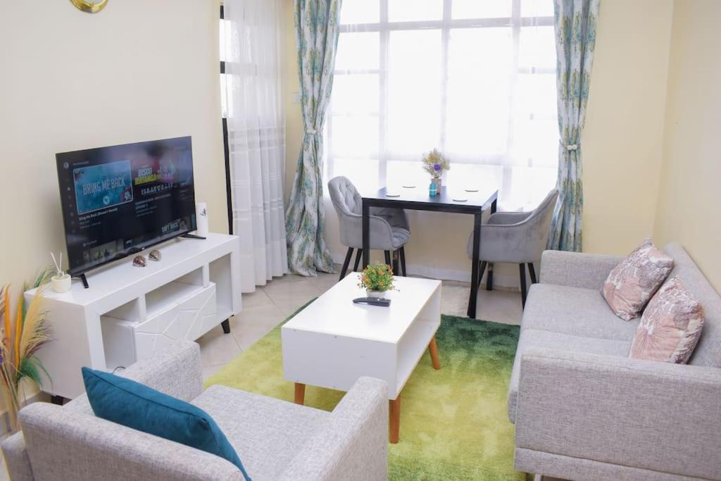a living room with a couch and a tv and a table at Marvel Homes in Meru