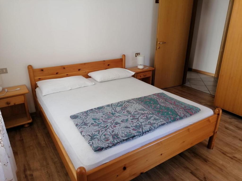 1 dormitorio con cama de madera con sábanas blancas en Belle Maison en Folgaria