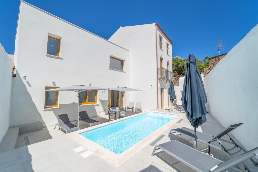 una piscina con sillas y sombrillas junto a un edificio en Nuova -Luxury Rooms & Apartment- en Olbia