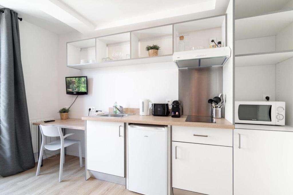 Elle comprend une cuisine avec des placards blancs et un bureau. dans l'établissement Lille Hypercentre/Railway stations -Nice studio, à Lille