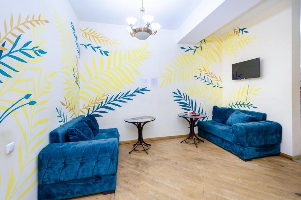 a living room with two blue chairs and a tv at Areva Hostel & Apartment in Yerevan