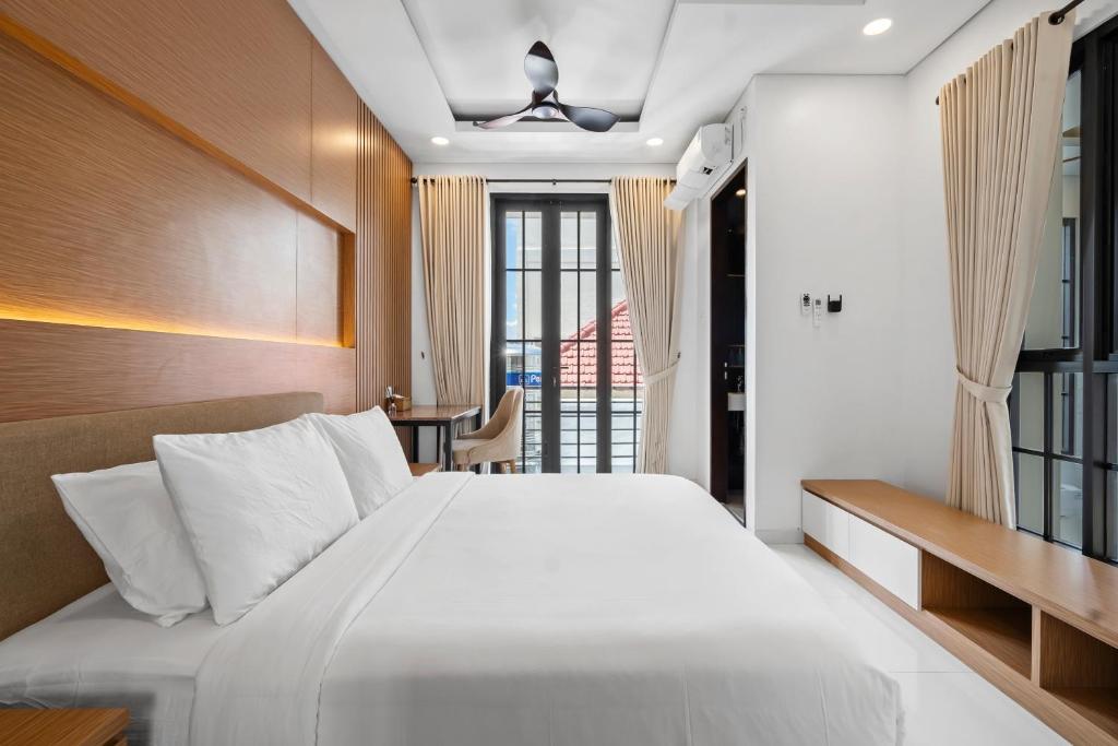 a bedroom with a large white bed and a desk at Asasta Villa by Betterplace in Tabanan