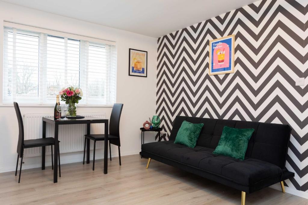 een woonkamer met een zwarte bank en een tafel bij Modern flat - Sleeps 3 - London in Enfield