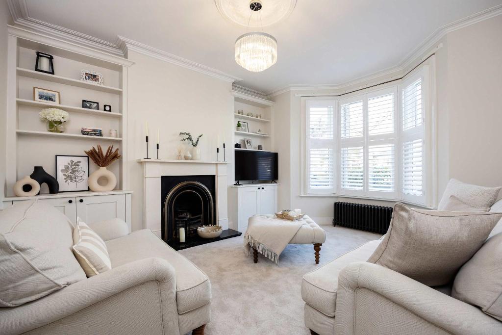 a living room with white furniture and a fireplace at Veeve - The Peace Lily in London