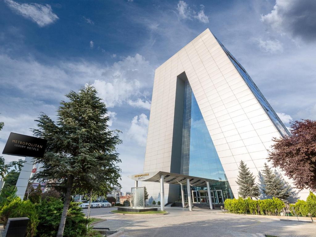 un edificio blanco alto con un árbol delante de él en Metropolitan Hotels Ankara, en Ankara