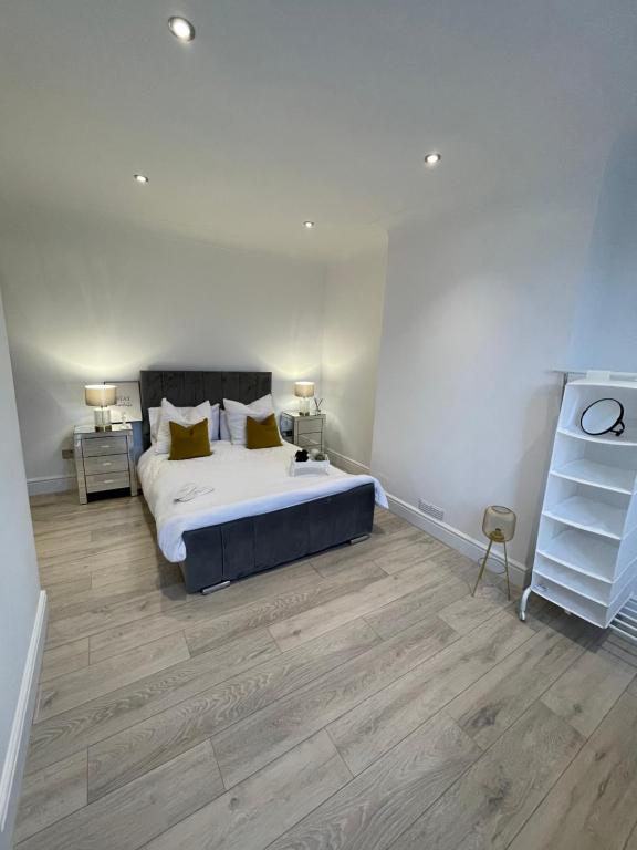 Luxury en-suite in modern house في Catford: غرفة نوم بسرير كبير وأرضيات خشبية