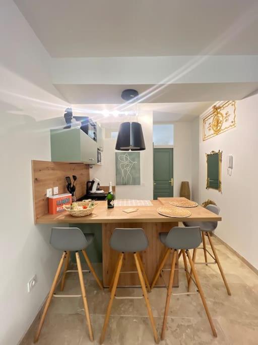 uma cozinha com um balcão de madeira com cadeiras à volta em Appart 1 chambre intra-muros avec JARDIN em Avignon