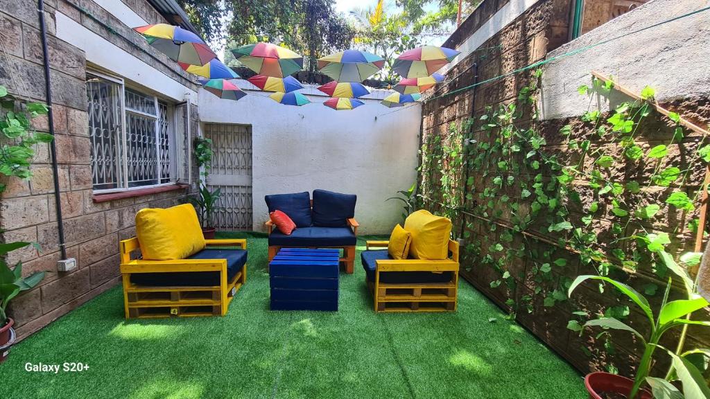 een patio met stoelen en parasols op het gras bij Jabulani Nairobi Backpackers Hostel in Nairobi