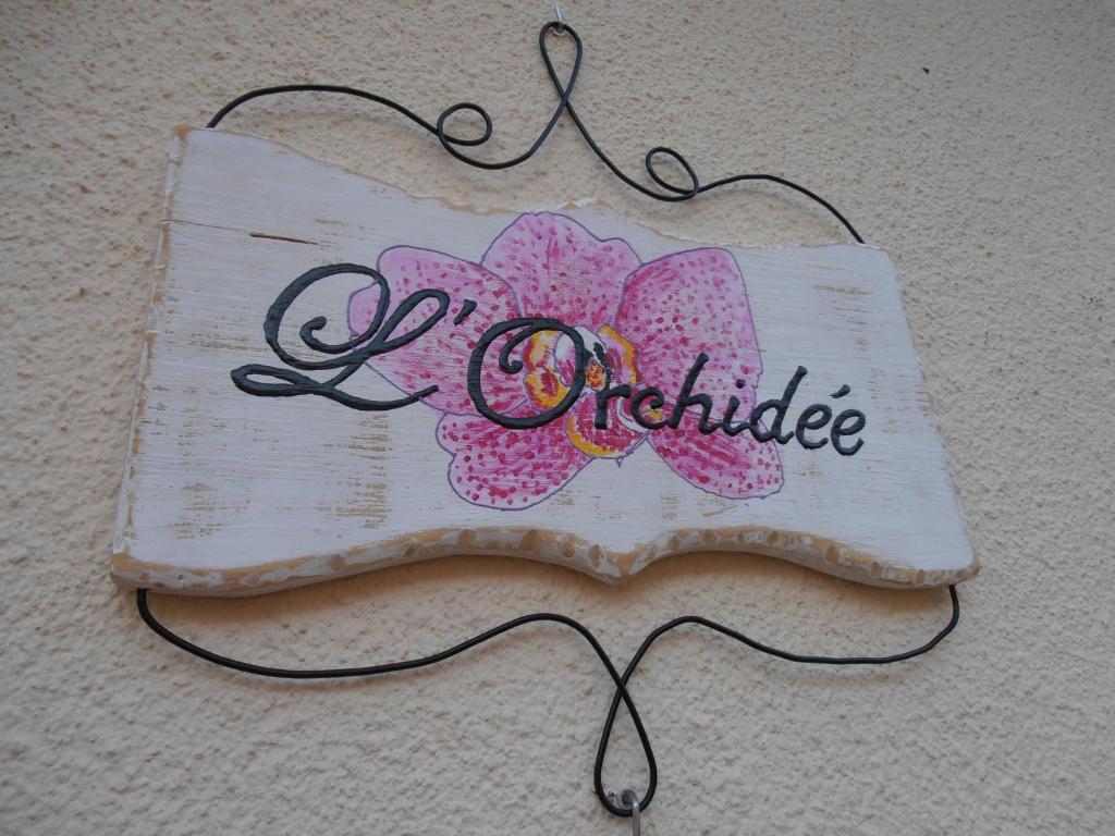 un cartel colgado en una pared con una orquídea rosa en L'Orchidée, en Ginestas