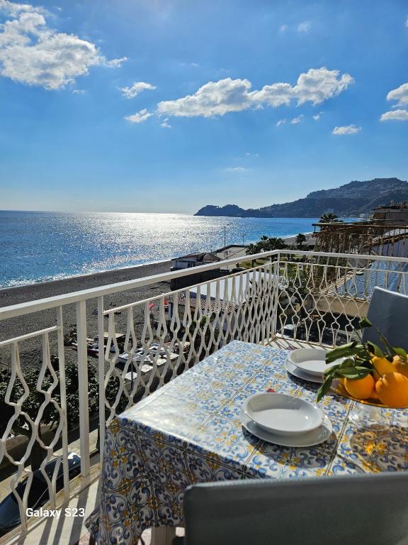 a table on a balcony with a view of the ocean at BAGLIO SUL MARE Letojanni Taormina in Letojanni