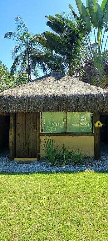 een kleine hut met een grasdak op een veld bij Pousada Bangalô de Barro in Paraty