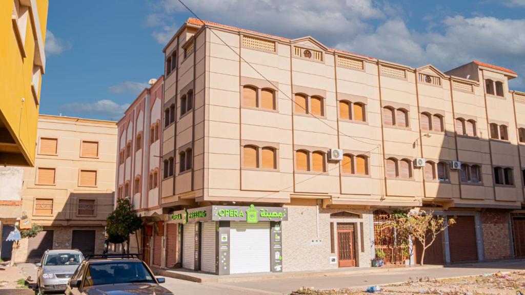 un bâtiment dans une rue avec des voitures garées devant elle dans l'établissement Airport Apartment M&A, à Nador