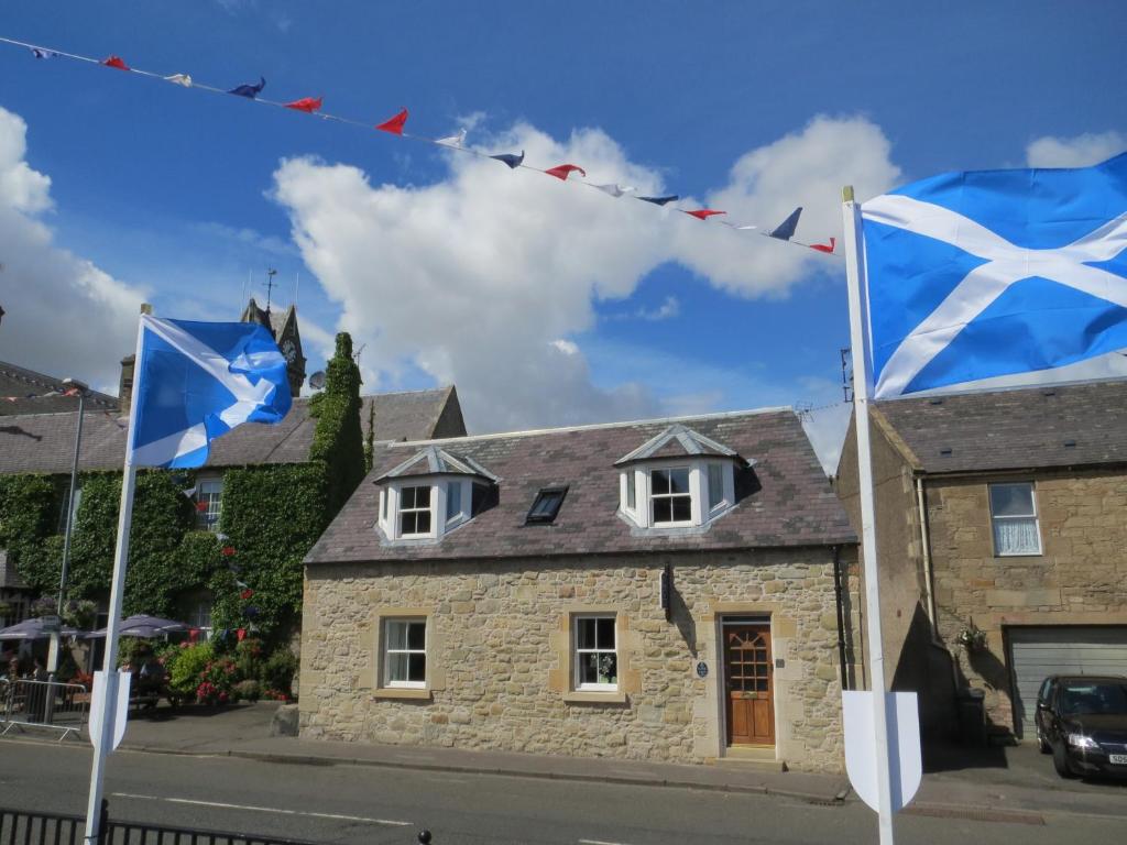 two flags flying in front of a house at Little Bethel Holiday Cottage in Coldstream