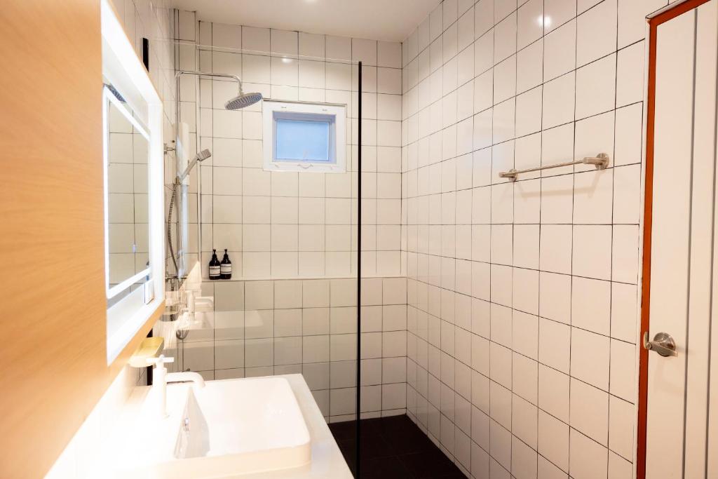 a white tiled bathroom with a sink and a shower at Karpenter Lampang in Lampang