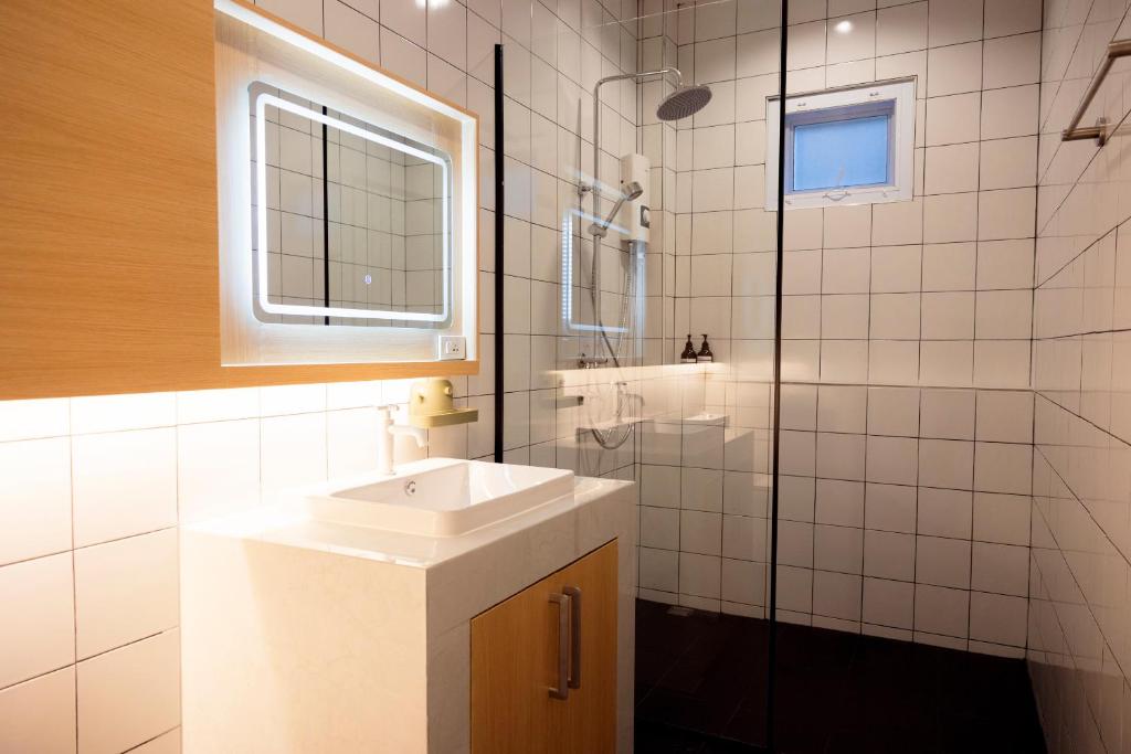 a white bathroom with a sink and a shower at Karpenter Lampang in Lampang