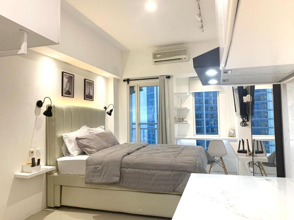 a white bedroom with a bed and some windows at Pakuwon Mall Dovey Apartment in Surabaya