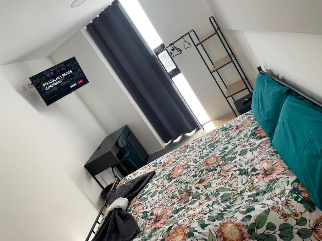 a small bedroom with a bed and a television at Hostal NANA B&B in Arroyo de la Encomienda