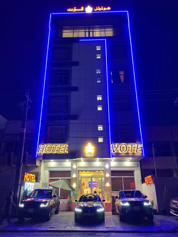a hotel with cars parked in front of it at night at Vote Hotel in Erbil
