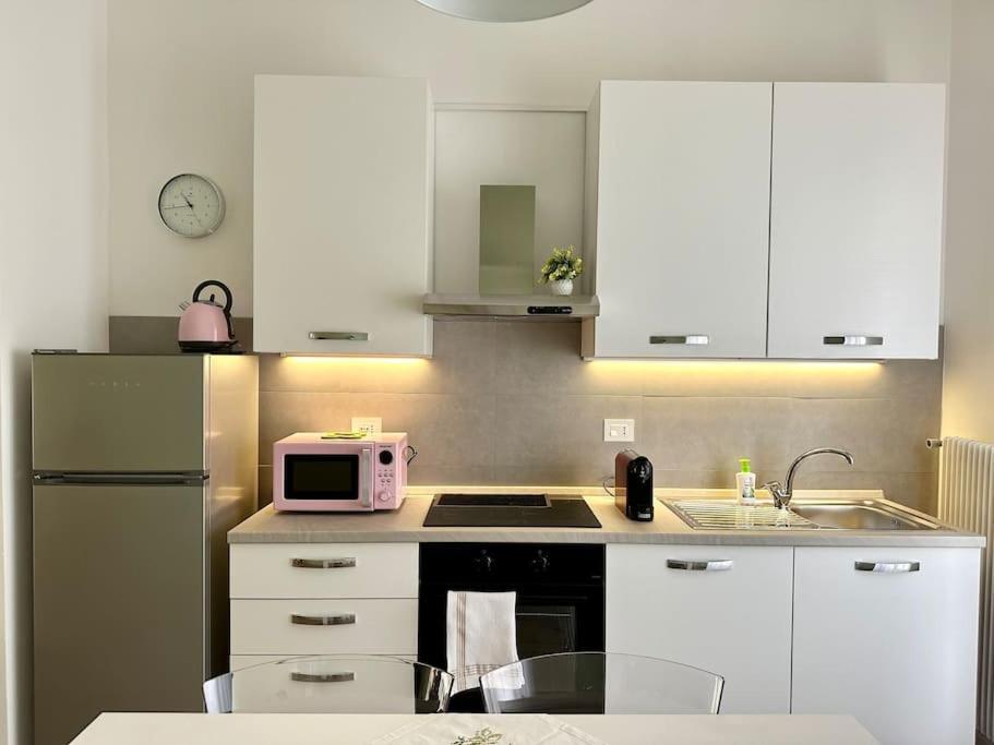 a kitchen with white cabinets and a pink microwave at Casa in centro storico Lago di Garda in Castelnuovo del Garda
