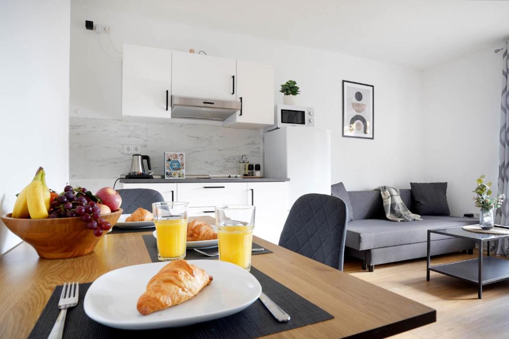 a table with a plate of croissants and glasses of orange juice at Schöne Apartments in Bad Rothenfelde I private Parkplätze mit Ladesäulen I home2share in Bad Rothenfelde