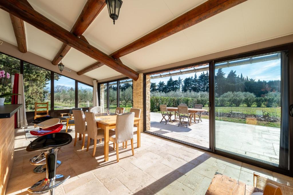 une véranda avec une salle à manger dotée d'une table et de chaises dans l'établissement Gîte du Mas Saint Paul - Maison avec piscine, à Travaillan