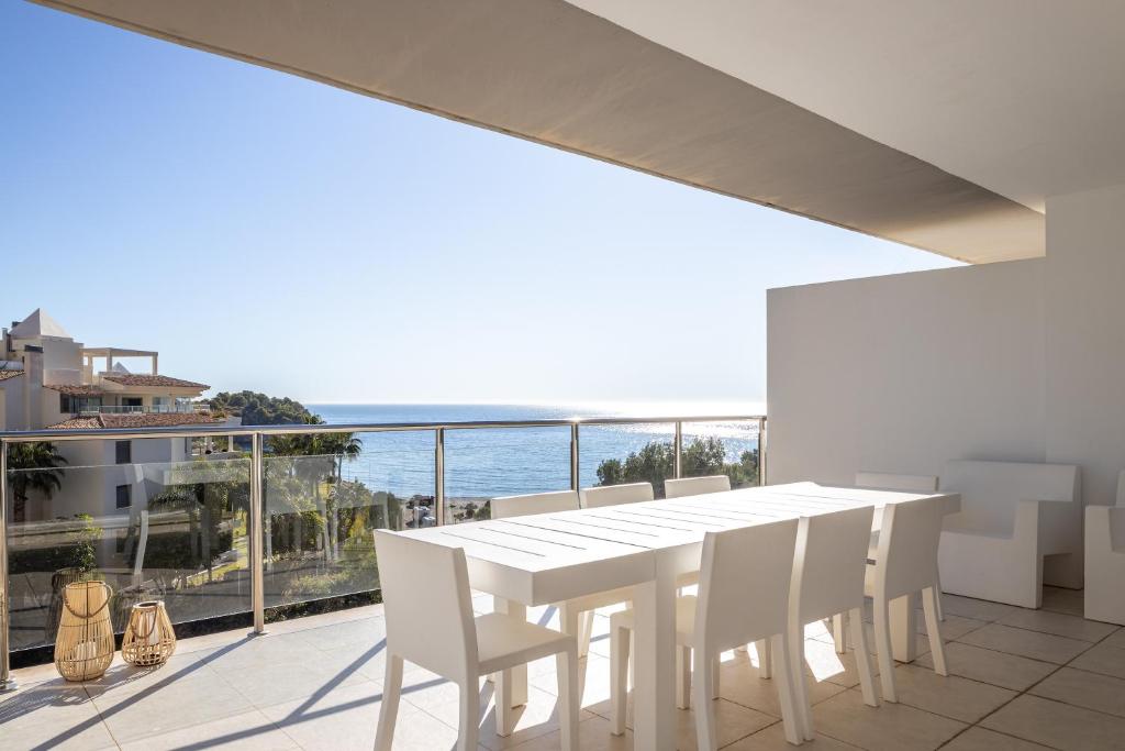a white dining room with a view of the ocean at Buccara Altea Beach Villas in Altea