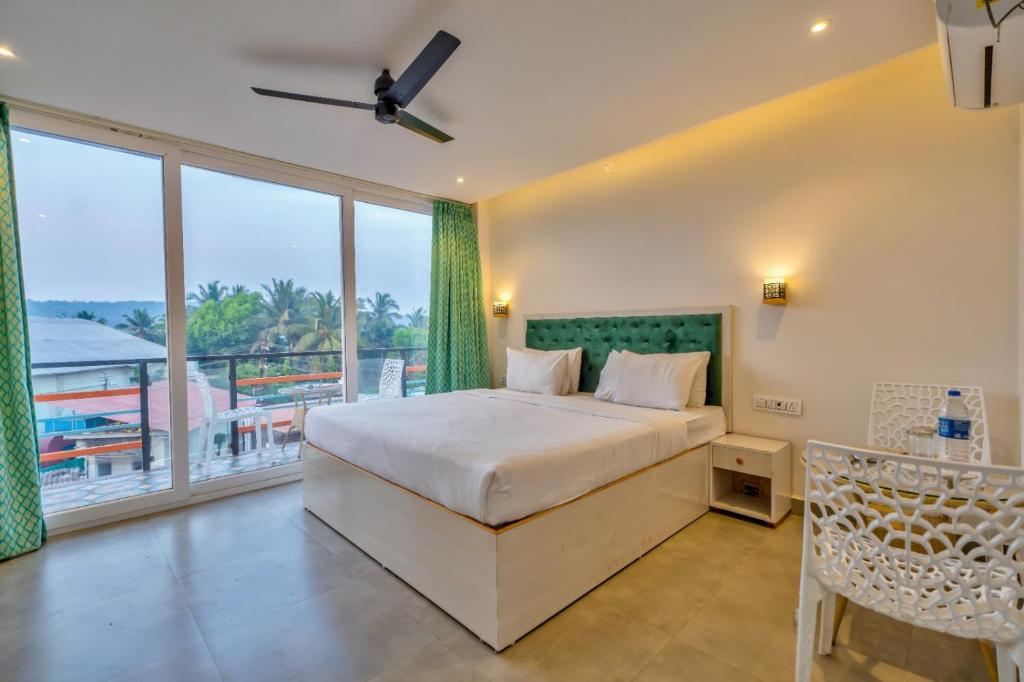 a bedroom with a bed and a large window at Baga Galaxy in Baga