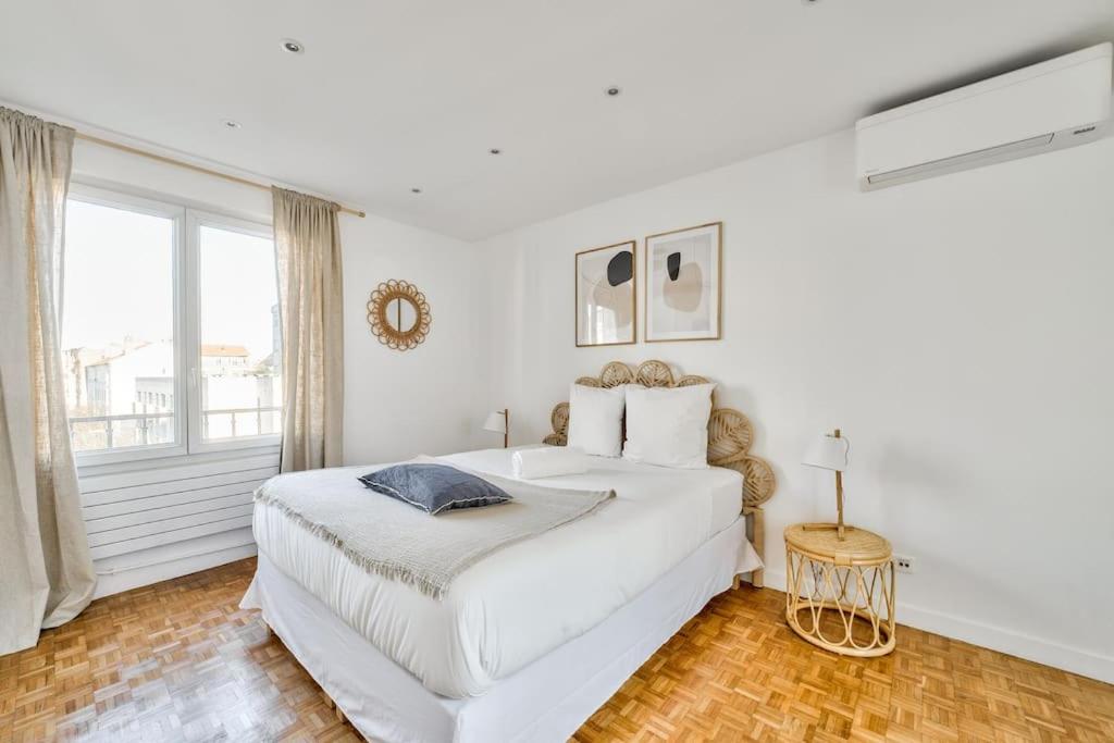 una camera bianca con un grande letto e una finestra di Superbe appartement terrasse 75m Paris a Saint-Mandé