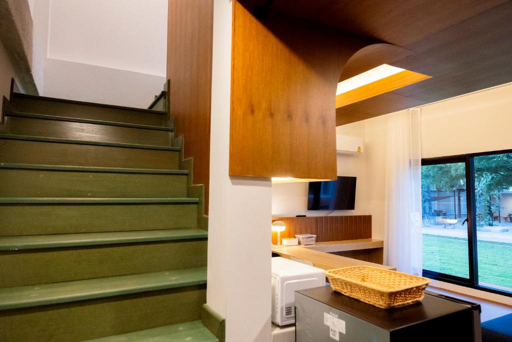 a living room with green stairs in a house at Karpenter Lampang in Lampang