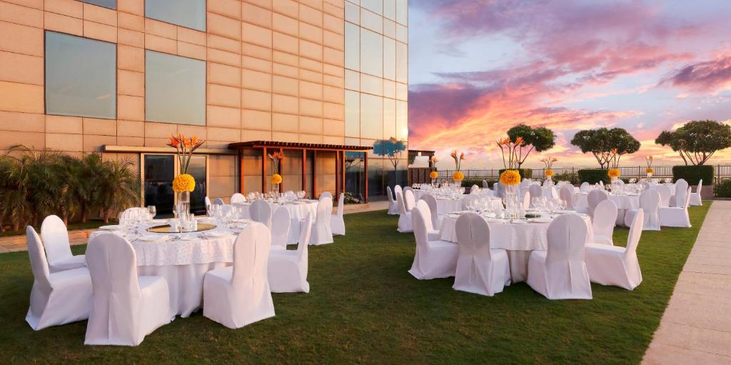 a group of tables and chairs in front of a building at The Leela Ambience Gurugram Hotel & Residences - The Luxury Urban Sanctuary in Gurgaon