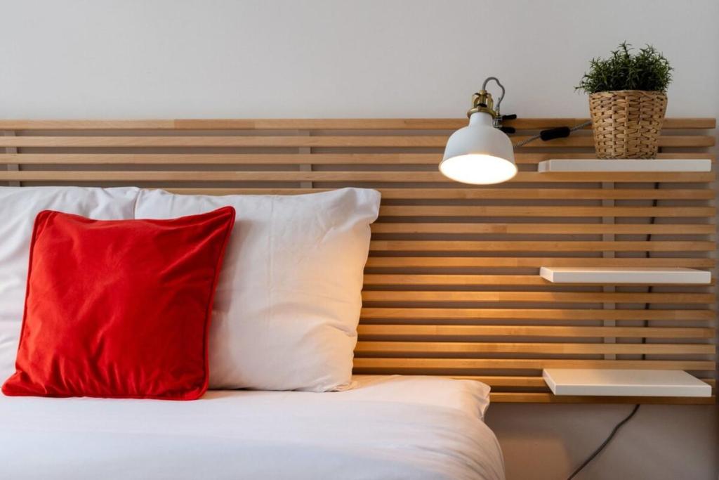 a red pillow on a bed with a wooden headboard at Vieux Lille appartement 1 chambre in Lille