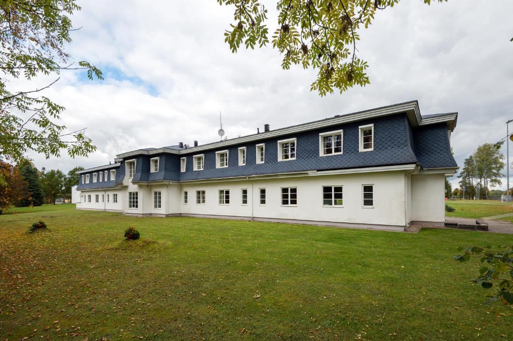 duży biały budynek z niebieskim dachem w obiekcie Staicele - Learning and Training Hub w mieście Staicele