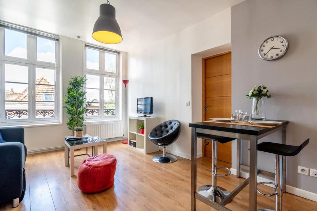 a living room with a table and a clock on the wall at Vieux Lille appartement 1 chambre in Lille