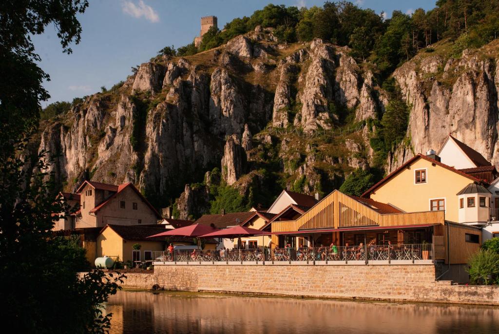 a restaurant on the side of a river with a mountain at Bierhotel - Hotel & Brauereigasthof Schneider in Essing