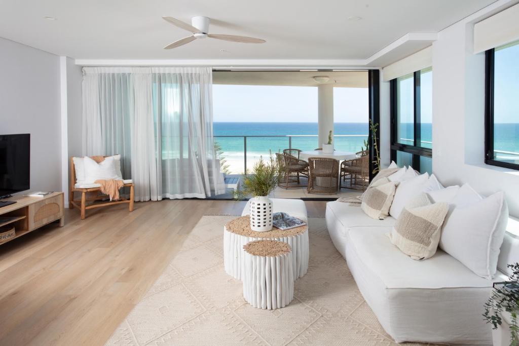 a living room with a white couch and a view of the ocean at Villa Sol - Luxury 3 Bedroom Villa in Kirra in Gold Coast