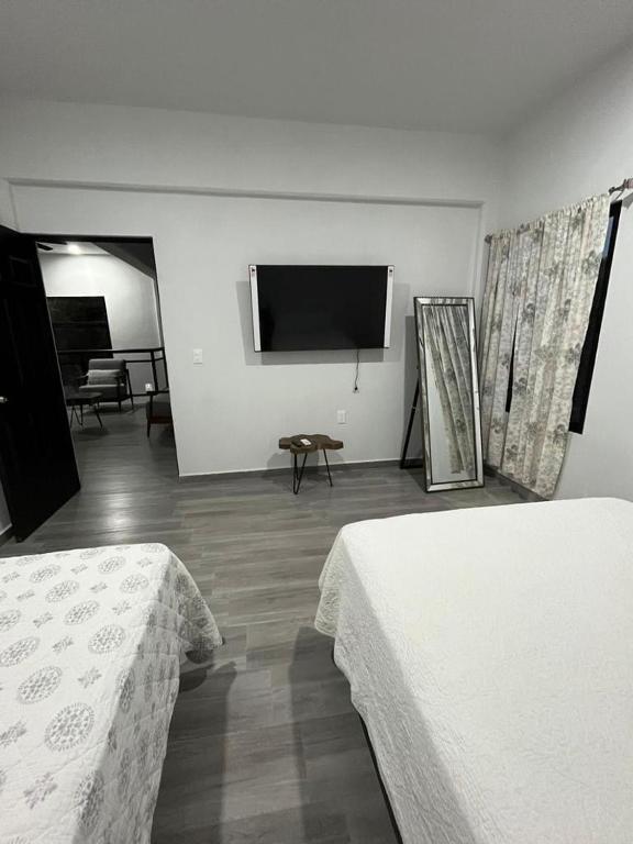 a bedroom with two beds and a flat screen tv at Casa Sac-Na in Bacalar